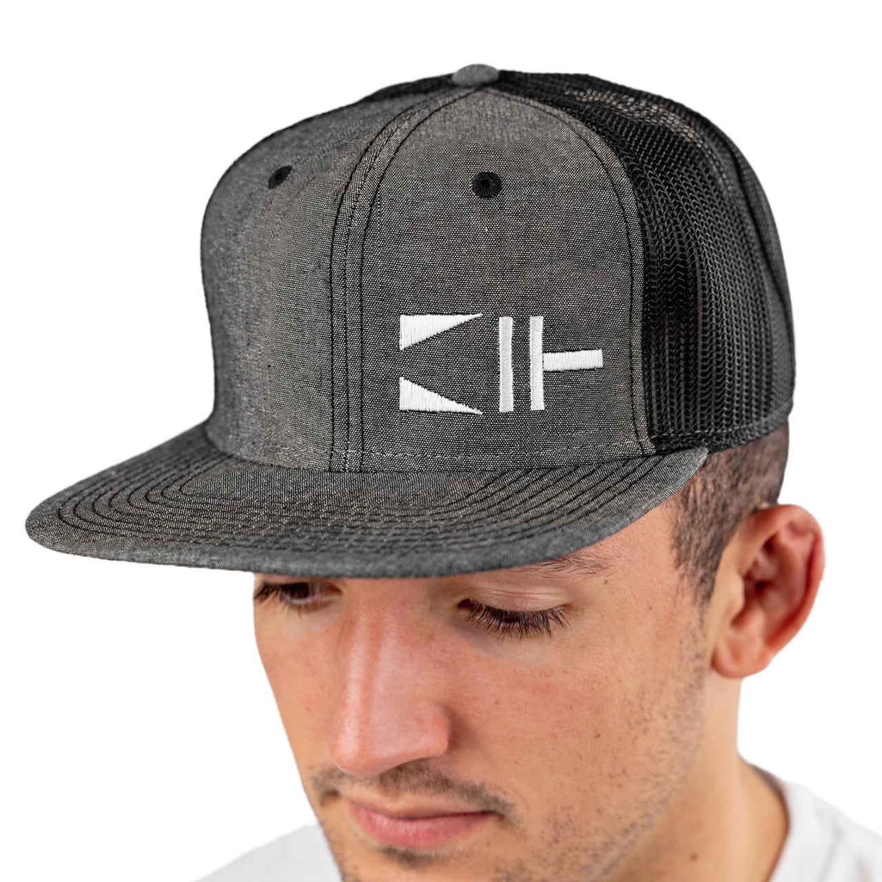 Paint Life Painters Trucker Hat. A person wearing a gray and black chambray trucker hat with a white paint brush logo on the front.